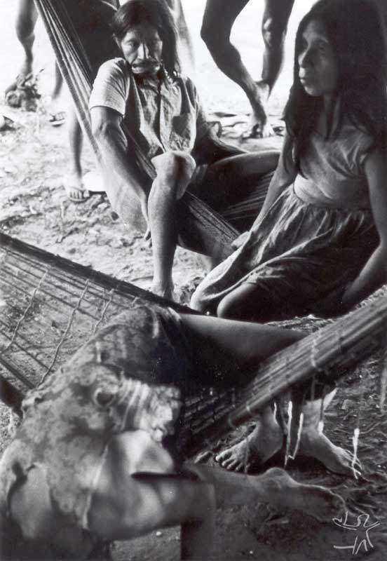 Tapayuna na aldeia suyá (mulher inclinada na rede sofre um ataque atribuído ao trauma de ter disputado sua mãe morta, na qual tentava mamar quando pequena, com um urubu). Foto: Eduardo Biral, 1985.