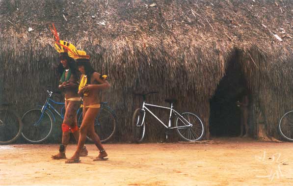 Mulheres kuikuru na aldeia Matipu por ocasião da festa Itão Kuegu (Yamurikumã), tendo ao fundo uma casa comunal. Foto: Camila Gauditano, 2001.