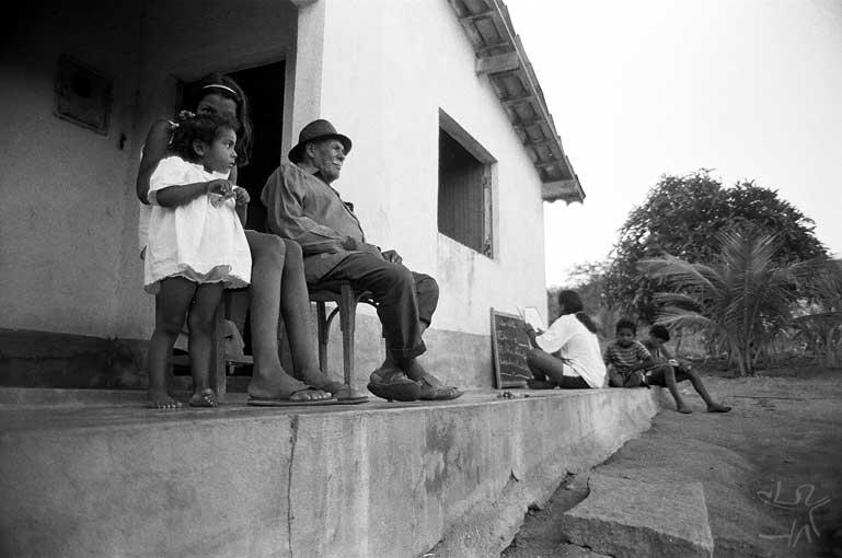 Aspecto de grupo residencial (constituído pela casa de patriarca, cercada pelas casas de filhos casados), com avô e netos na calçada. Foto: José Maurício Arrutti, 1994.