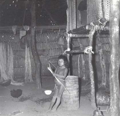 Criança Canela Ramkokamekrá no interior de uma habitação na aldeia do Escalvado. A cama elevada é de uma moça recém-casada sem filhos, para que apenas seu marido possa vê-la. Foto: Willian Crocker, 1969.
