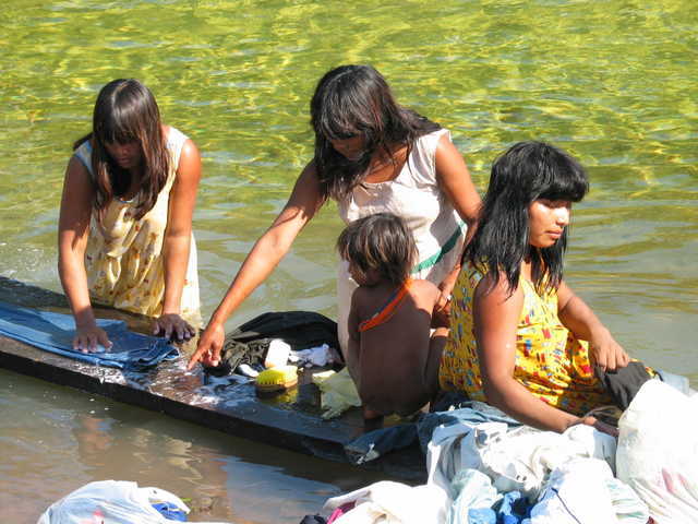 Criança Nambikwara Mamaindê observa mulheres lavando roupa na beira do rio, Aldeia Central, Mato Grosso. Foto: Kristian Bengtson, 2003.